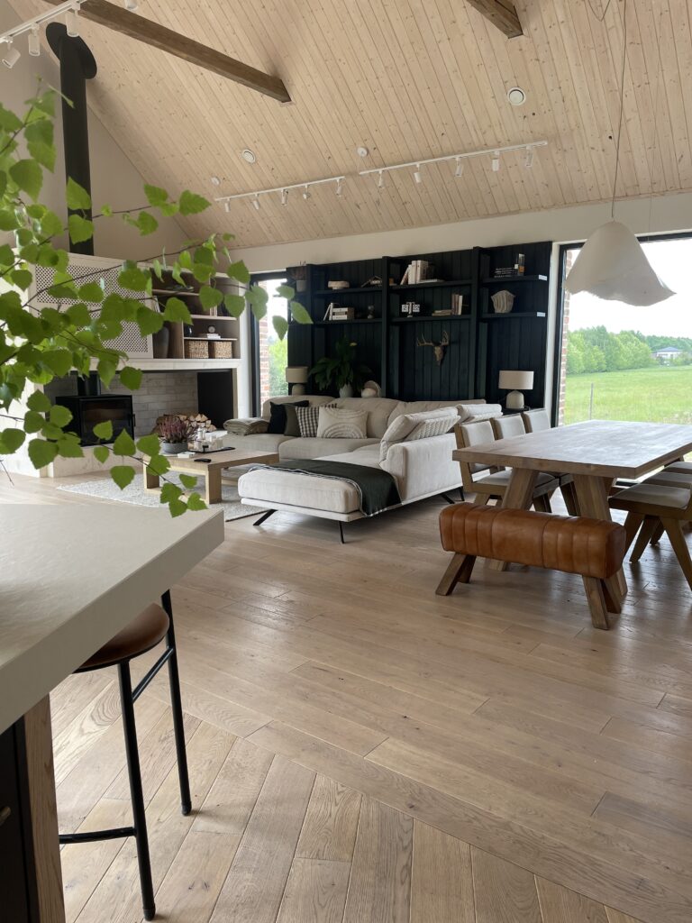 Wnętrze domu Zagroda Śląska zaprojektowane przez SOHA – jasny salon z drewnianym stołem, kominkiem i naturalnymi materiałami w stylu slow life.