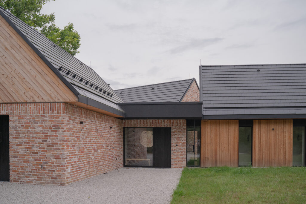 Detal wejścia do domu Zagroda Śląska zaprojektowanego przez SOHA – ceglana elewacja z drewnianymi elementami i minimalistyczną linią dachu.